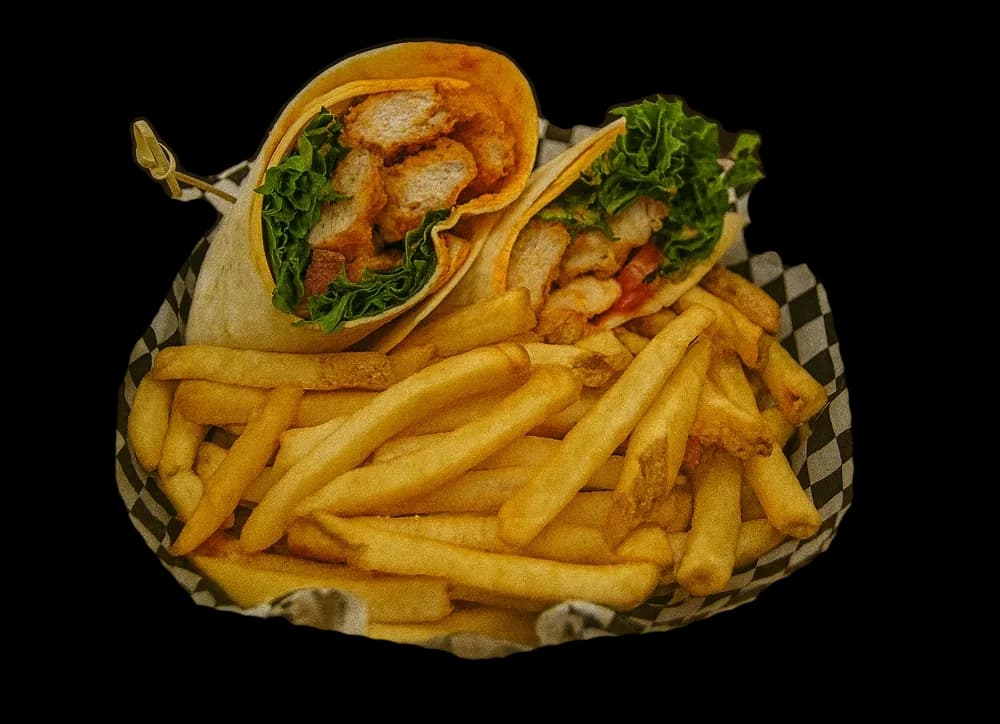 A grilled buffalo chicken wrap with fries in a checkered basket